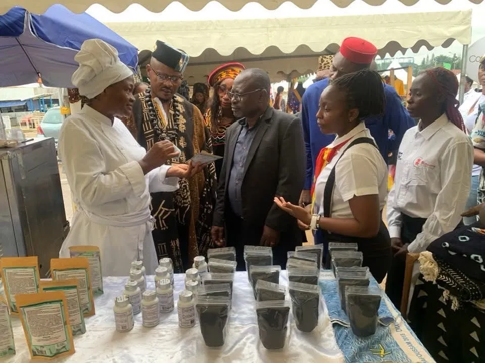 Exposante en tenue de chef présentant ses produits sous les tentes de la foire